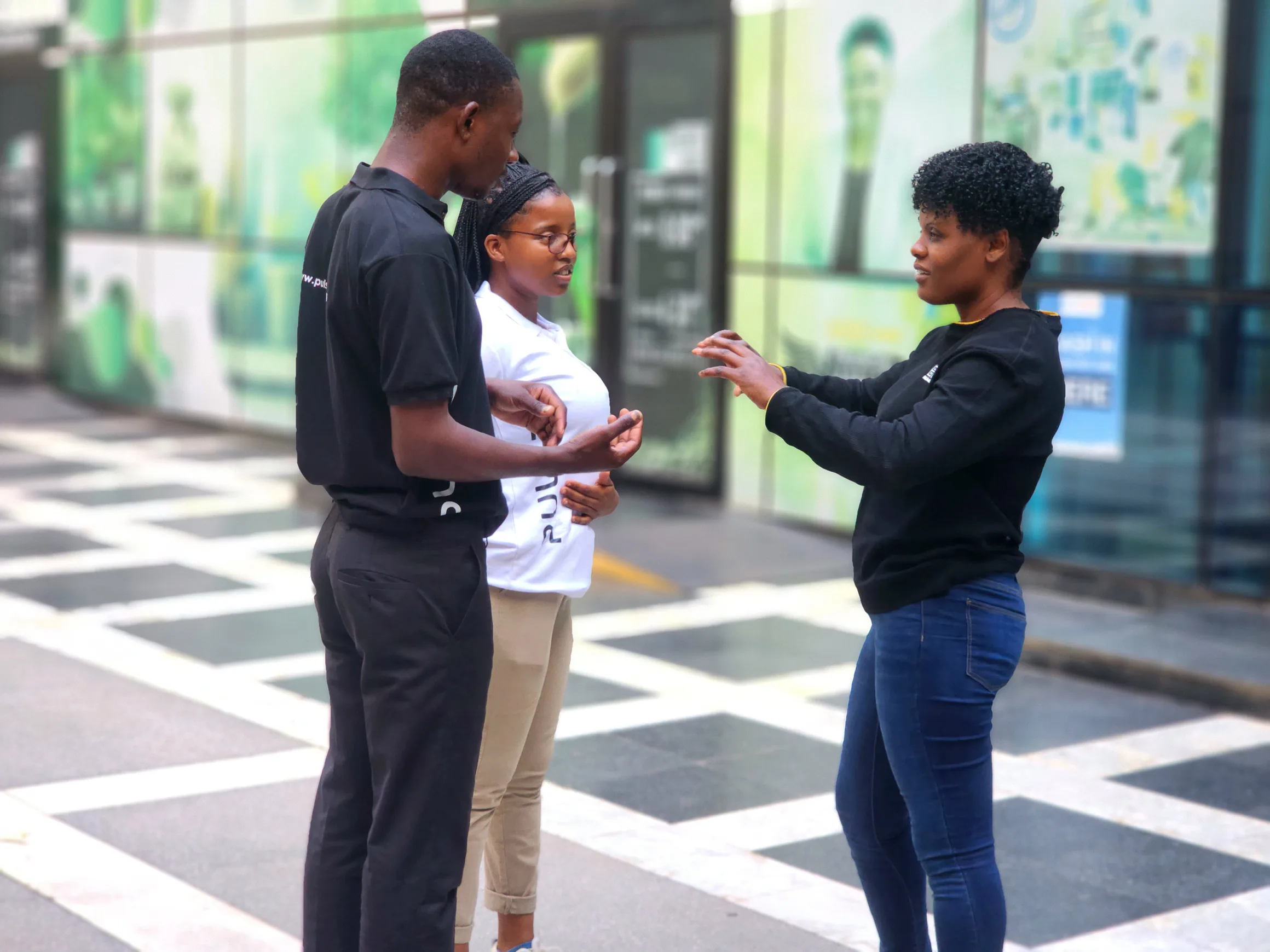 Three members of the PULSE team talking outside an office building in Harare